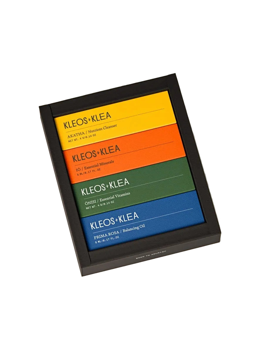 A black square frame or tray holding four horizontal color panels labeled KLEOS-KLEA in yellow, orange, green, and blue, photographed on a plain light beige background.